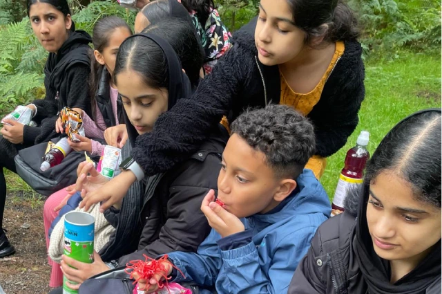 Children sat in nature eating snacks and laughing